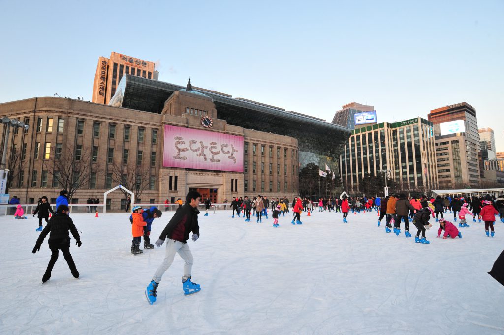 ผู้คนมากมายกำลังเล่นสเกตน้ำแข็งอยู่ในลานสเก็ตกลางแจ้ง
